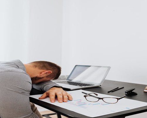 एक व्यक्ति ऑफिस डेस्क पर थका हुआ बैठा है